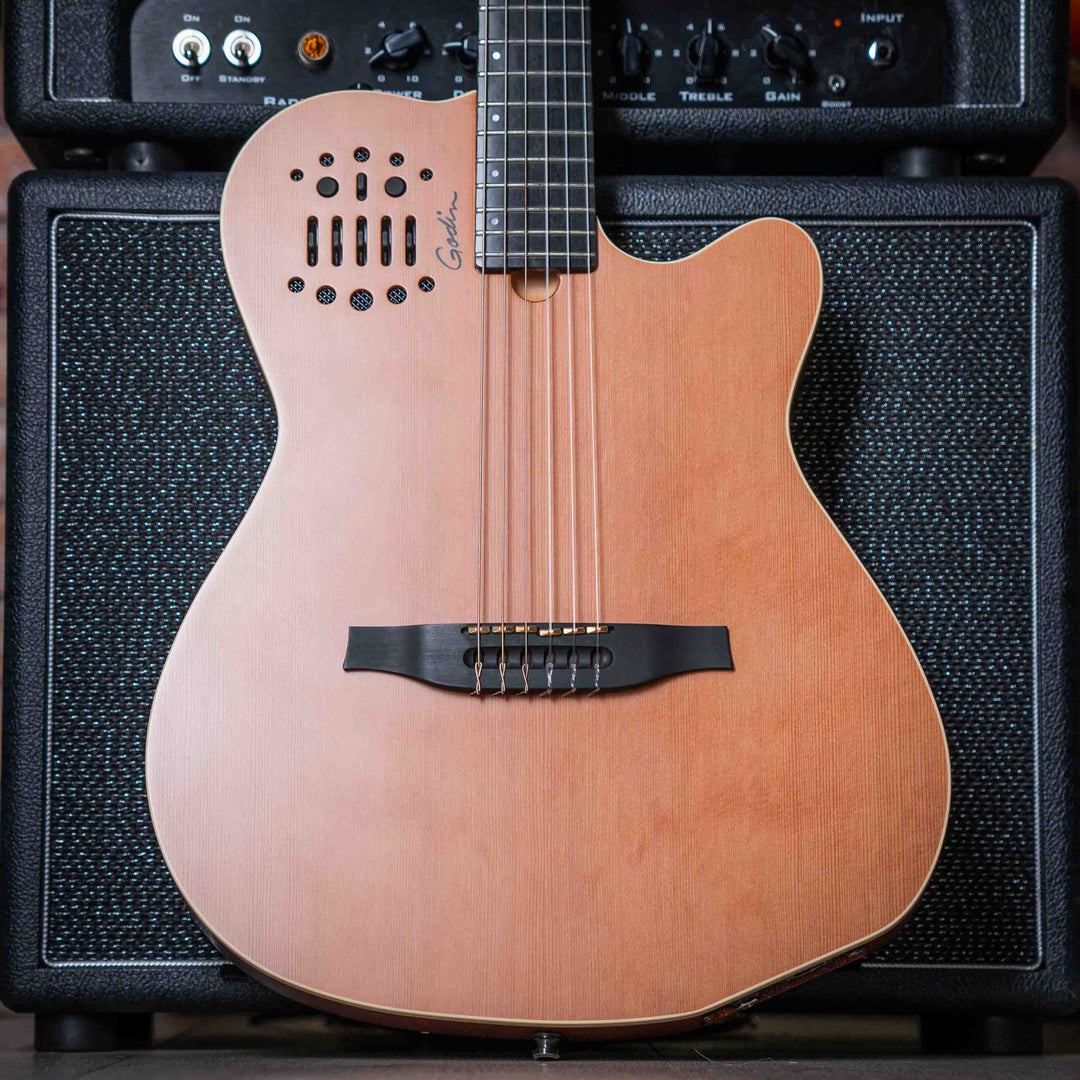 Godin Multiac Nylon ACS SLIM SA - Guitarra Electroacústica | Godin Multiac Nylon ACS Slim SA Slim' se refiere al ancho de la cejilla de 1,715″, que es apenas 16 de pulgada más ancho que el ancho de la cejilla de nuestras guitarras eléctricas estándar. Si