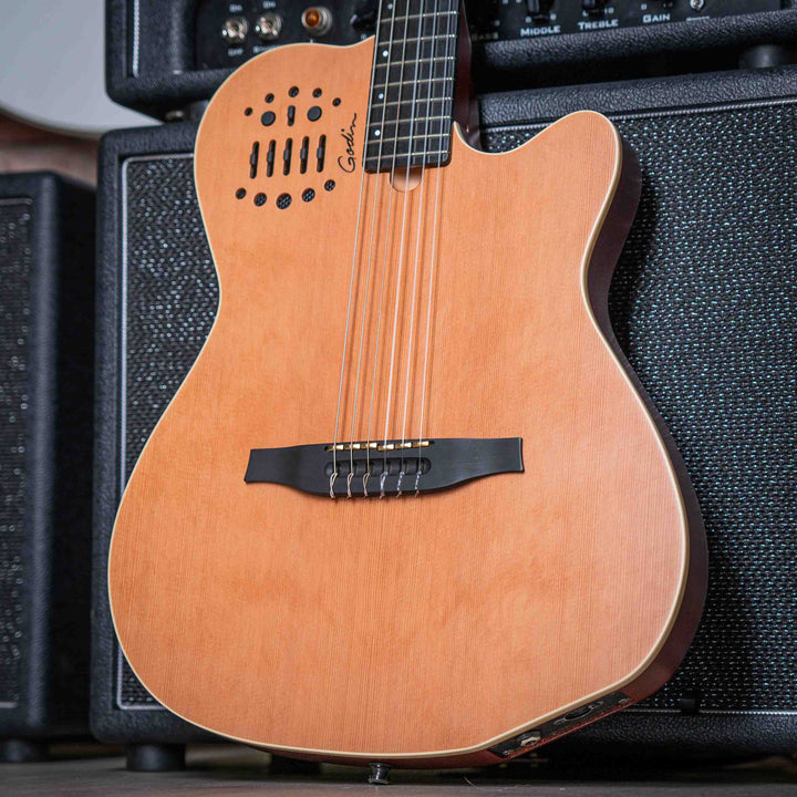 Godin Multiac Nylon ACS SLIM SA - Guitarra Electroacústica | Godin Multiac Nylon ACS Slim SA Slim' se refiere al ancho de la cejilla de 1,715″, que es apenas 16 de pulgada más ancho que el ancho de la cejilla de nuestras guitarras eléctricas estándar. Si