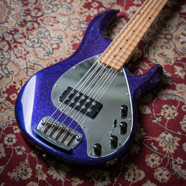 Musicman Stringray 5 Sparkle Purple 1999 - Bajo Eléctrico | Cuerpo • Modelo: Stingray Classic• Madera: Ash• Terminación: Polyurethane Sparkle Brazo • Madera: Maple• Perfil: “C”• Terminación: Satin • Espaciado: 19 mm• Escala: 34” • Nuez: Hueso Diapasón • M