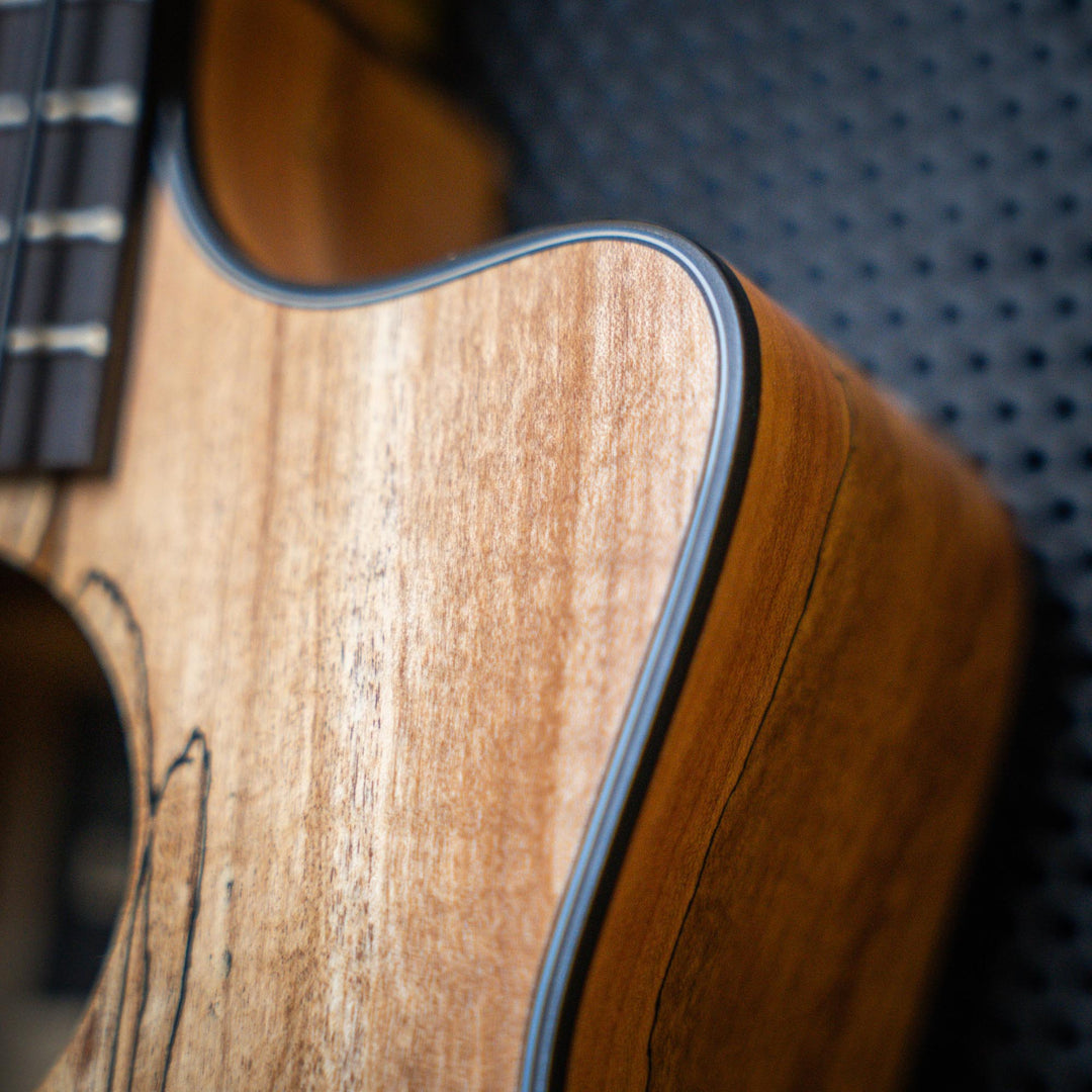 Ubass Kala Sp-Mapl-Fs - Bajo Ukulele | El Ubass Kala SP-MAPL-FS tiene grietas en la madera que se asemejan a garabatos de punta fina que forman líneas negras onduladas y rayas que contrastan maravillosamente con el arce de dos tonos de color más claro. El