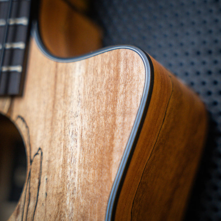 Ubass Kala Sp-Mapl-Fs - Bajo Ukulele | El Ubass Kala SP-MAPL-FS tiene grietas en la madera que se asemejan a garabatos de punta fina que forman líneas negras onduladas y rayas que contrastan maravillosamente con el arce de dos tonos de color más claro. El