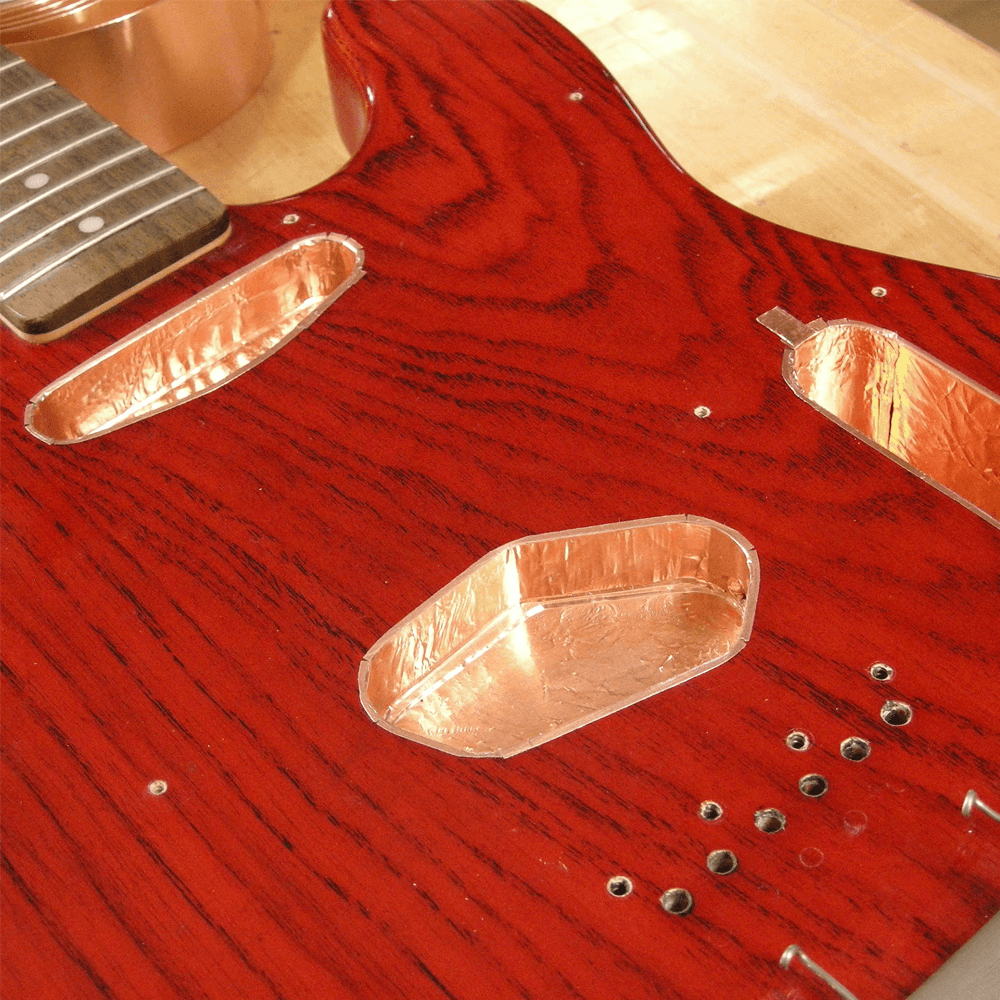 Blindaje & Apantallado | El blindaje de las cavidades donde se aloja la electrónicas consiste en dar tres manos con pintura conductiva especializada para luego apantallar con láminas de cobre adhesivo, lo cual mantiene a tu instrumento libre de ruidos y s